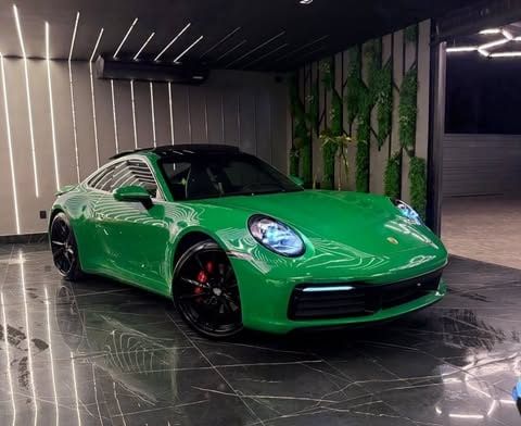 Porsche 911 Carrera verde no showroom de piso de mármore preto