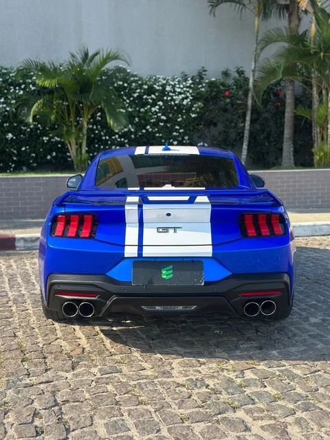 Ford Mustang na cor azul com faixas brancas, vista de trás
