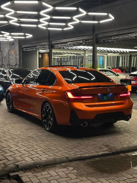 BMW 320i com envelopamento laranja, vista traseira em três quartos (foto 4 de 20)