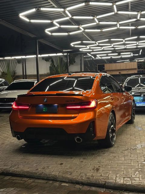 BMW 320i com envelopamento laranja, vista traseira em três quartos (foto 6 de 20)